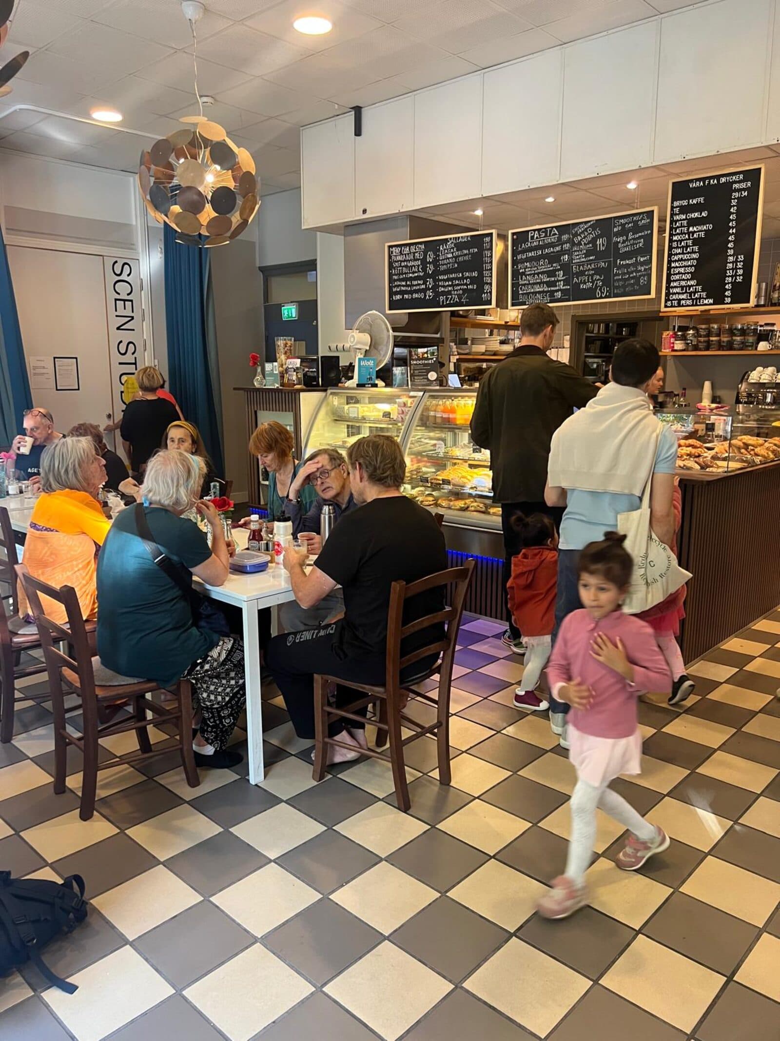 Gäster som fikar i den ljusa lokalen på Kafé Arte vid Jarlaplan